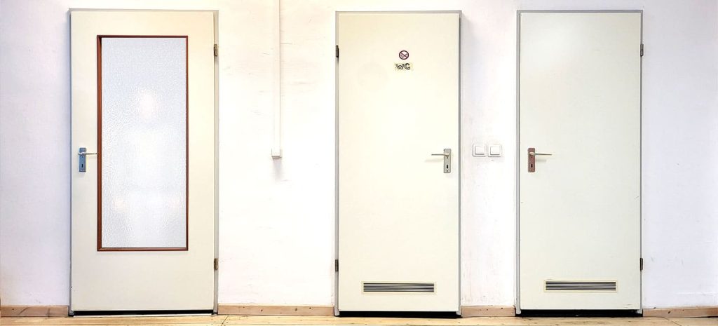 Frontal Foto von drei Türen an einer Weißen Wand nebeneinander